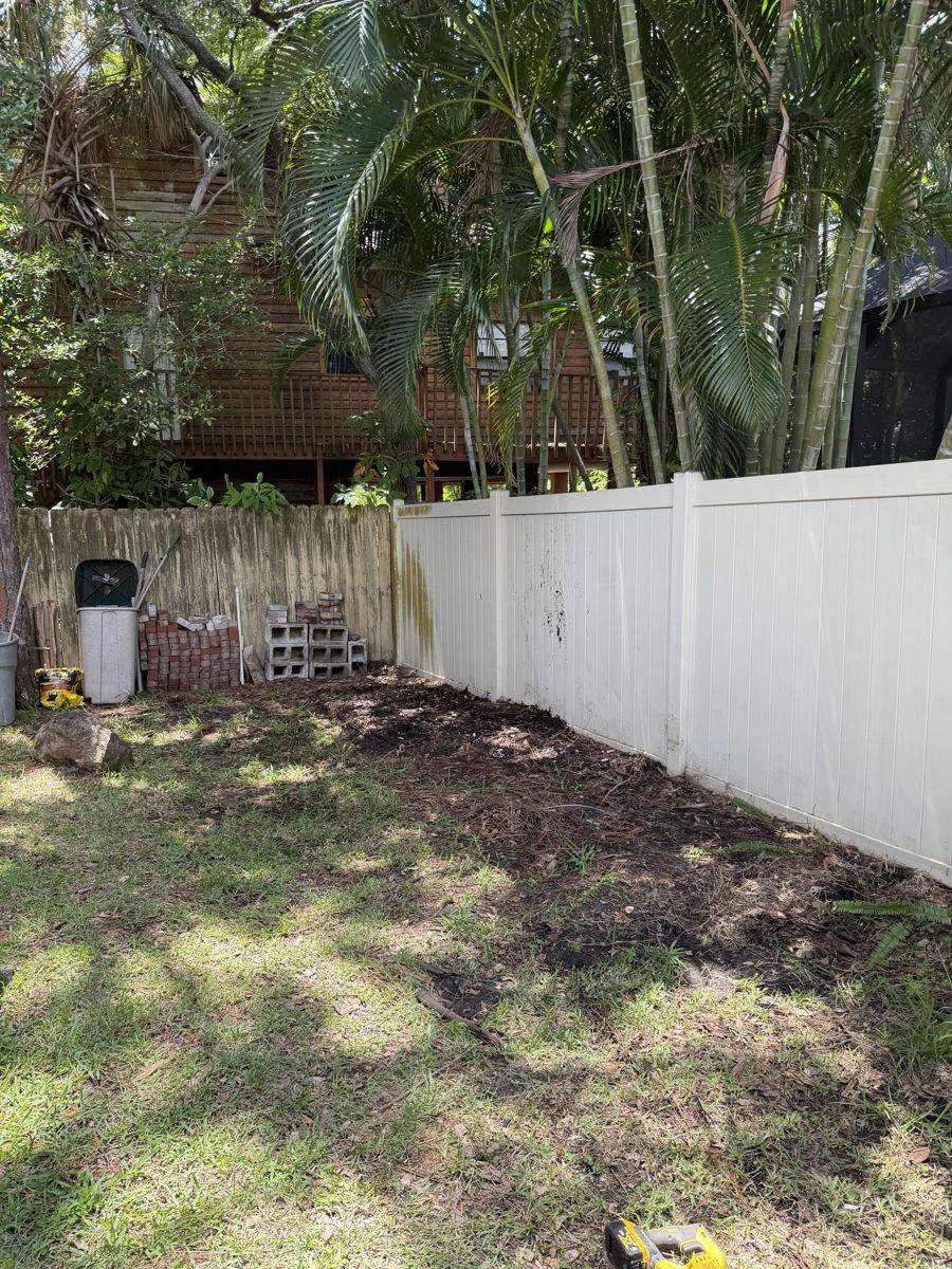 Side yard cleared and cleaned up along a vinyl fence in Dunedin, FL